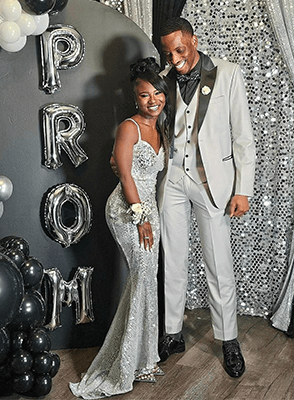 A teenage girl and boy posing together in formal prom attire.