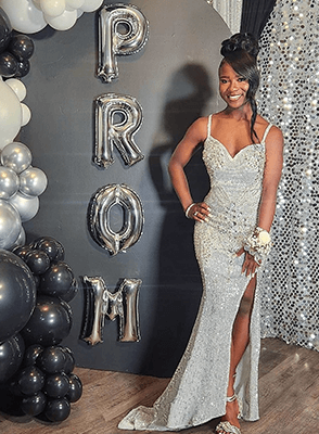 A young lady dressed up for prom, posing confidently.